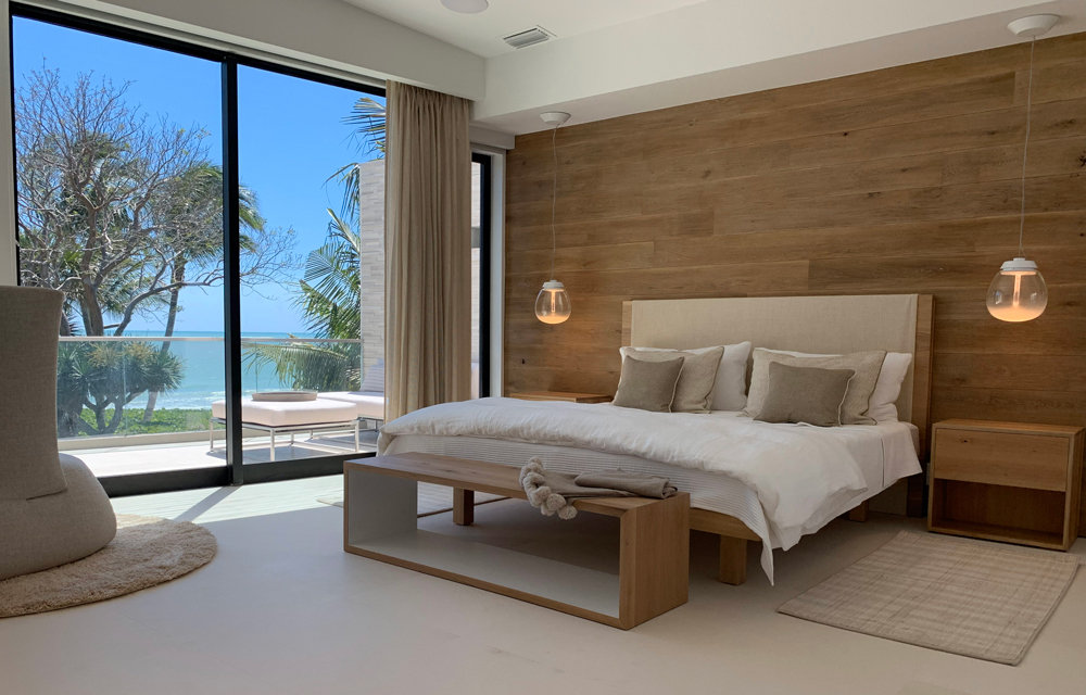 master bedroom with a full glass wall and a view of the ocean
