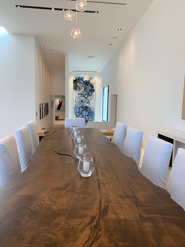 long wooden table with white chairs view from the head of the table